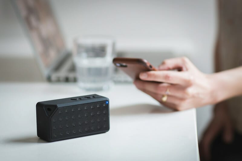 Canva Person Holding Iphone Beside Black Portable Speaker